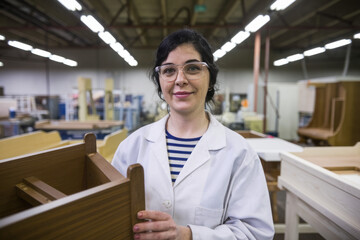 Fototapeta premium Woman holding woodwork. Female worker holding a piece of wood, showing pride and expertise in her craft.