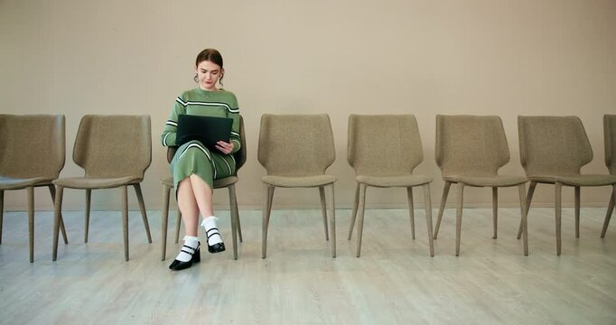 Waiting room, woman and thinking with laptop for job interview, vacancy process and business hiring. Chairs, candidate and prepare with cv for creative agency, recruitment and designer opportunity