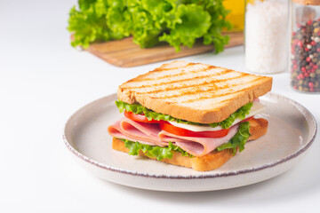 Close-up of two sandwiches with bacon, salami, prosciutto and fresh vegetables on rustic wooden cutting board. Club sandwich concept