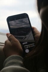 Capturing the view from an airplane window during a cloudy flight over mountainous terrain