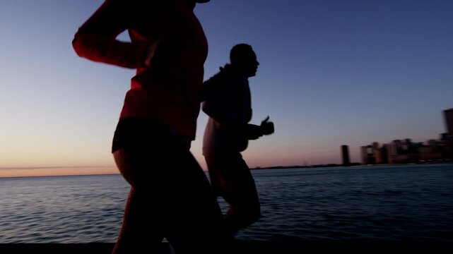 Silhouette of Multi Ethnic male and female at sunrise in Chicago fitness running