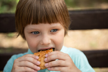 Child eating homemade cakes outdoors. Little boy enjoying chocolate sweet dessert snack. Street food