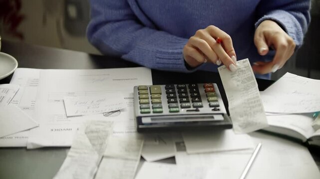 Woman calculating finances with calculator and receipts