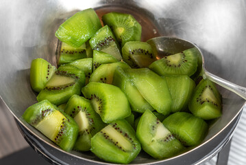 Kiwi pieces with spoon in stainless steel bowl