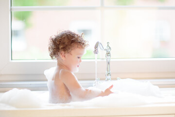 Naklejka premium Baby taking bath in kitchen sink