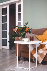 A Cozy Living Room Featuring a Soft Blanket, Lush Green Plants, and a Warm Cup of Coffee