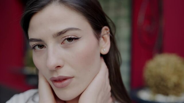 Intimate close-up of a young Caucasian woman featuring her subtle smile and serene gaze against a vibrant red background. Close-Up Portrait of Young Woman with Subtle Smile in a Red Room