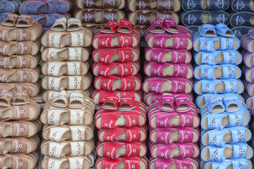 
rows of indoor slippers piled on top of each other on shelves in display cases
