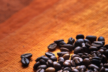 Coffee beans background photo taken in close up. Dark roasted brown beans with unique textures kept in pile.