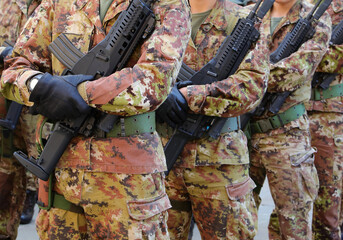 platoon of army soldiers standing at attention with camouflage uniform and assault rifle during the...