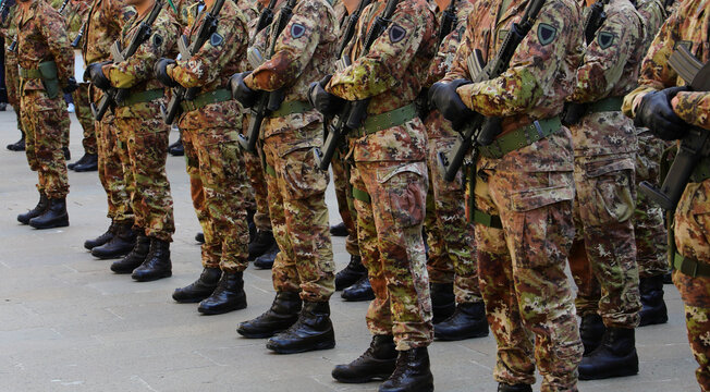 platoon of many army soldiers in camouflage uniform and assault rifle during parade and black boots