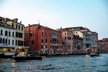Scenic waterfront view of colorful buildings along a canal in Venice at sunset with boats cruising by