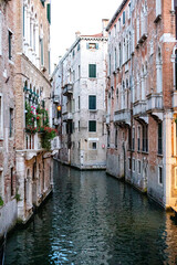 Narrow canal bordered by historic buildings in Venice at dusk, reflecting warm light on tranquil water surface