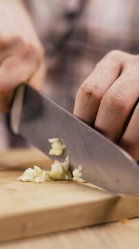 Male chef Chopping garlic with knife on a cutting board
