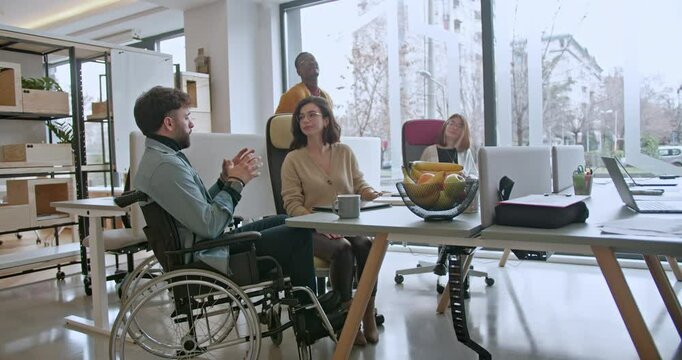 The inclusive office team collaborates on business strategy, utilizing digital devices and paperwork, demonstrating their commitment to effective communication and teamwork.