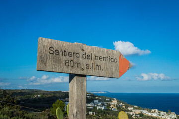 Un cartello di legno che indica la direzione per il Sentiero del nemico lungo il Cammino del Salento che da Lecce porta a Santa Maria di Leuca