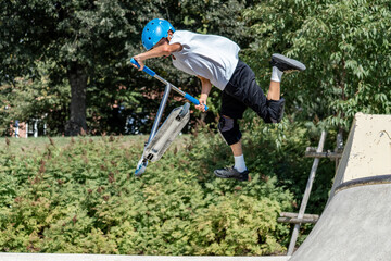 Young boy jumping with scooter freestyle in urban skatepark- jump tricks on scooter- freestyle, sport, extreme concept.   © Edijs