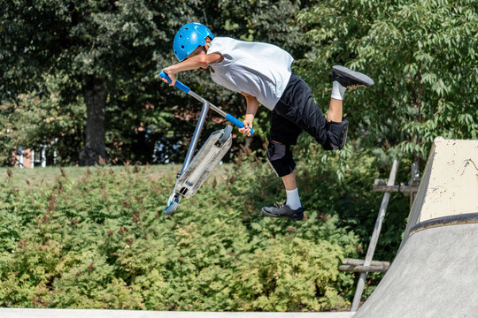 Young boy jumping with scooter freestyle in urban skatepark- jump tricks on scooter- freestyle, sport, extreme concept. 
