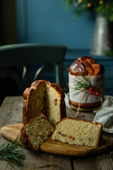 Two homemade Christmas panettone , one cut and the other whole, on wooden table on rustic kitchen with blue furniture.
