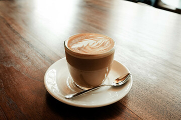 Cortado in a glass with a saucer and spoon