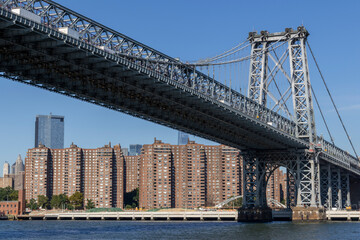 Fototapeta premium A clear day view of the Manhattan skyline and Williamsburg Bridge with modern skyscrapers under a blue sky
