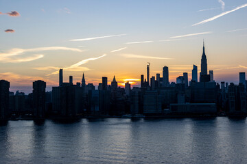Fototapeta premium Stunning sunset over the New York City skyline highlighting iconic buildings and reflections on the water