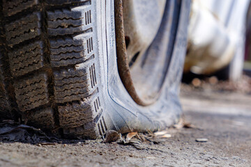 an old flat car tire. a puncture in a car tire. a hole in a tire and low tire pressure due to a puncture or long periods of standing without driving