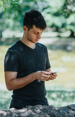 Fototapeta premium Young man using his smart phone in a peaceful park setting