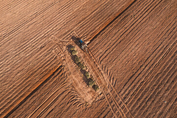 Aerial top view tractor plowing a field , preparing the land for a wheat planting operation.