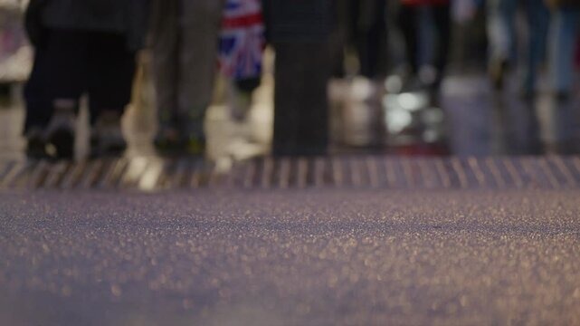 A vibrant and bustling city street scene is vividly captured, highlighting the wet pavement that reflects the dynamic energy of pedestrians moving energetically through the persistent rain