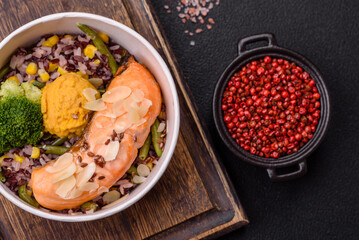 A piece of boiled salmon with rice, broccoli, salt and spices