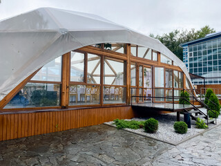 A modern glass structure seamlessly integrated with wooden elements set against a picturesque rainy...