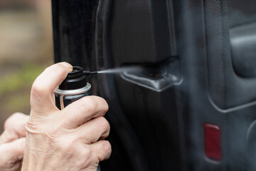 Man sprays car door lock to protect from freezing - winter