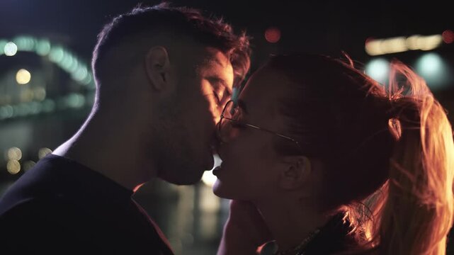 Two lovers kissing in lighting of urban streets