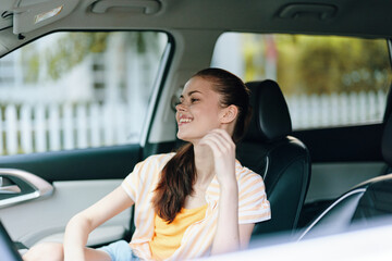 Young woman smiling in a car, enjoying a sunny day with natural light streaming in, wearing a casual outfit, reflecting a carefree and relaxed mood