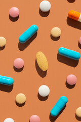 Pattern of several pills and tablets blue, pink, yellow and white colors on brown background. Creative tablets concept