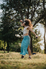 A young woman feeling free and expressive while performing a modern dance in a sunlit park. The natural surroundings and warm sunlight enhance the joyful mood.