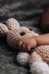 Sweet tiny newborn baby's hand hugging stuffed beige rabbit toy