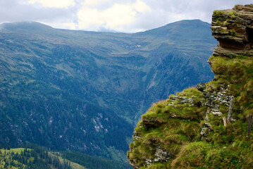 View of an amazing mountain landscape on a hazy day with gray clouds and fog over the peaks in autumn in Austria.