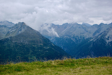 Fototapeta premium View of an amazing mountain landscape on a hazy day with gray clouds and fog over the peaks in autumn in Austria.