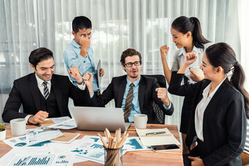 Group of happy businesspeople in celebratory gesture and successful efficient teamwork. Diverse race office worker celebrate after made progress on marketing planning in corporate office. Meticulous
