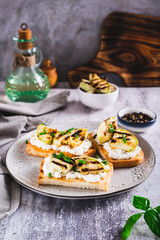 Sandwiches with ricotta, grilled zucchini and green onions on a plate vertical view