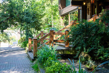 Obraz premium Garden with stone walkway and green plants in the park. Restaurant in a tropical garden. Wooden build in the park on a background of green trees.