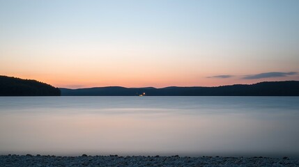 Fototapeta premium A vast expanse of water with a vessel bobbing at its center and distant mountains on the horizon