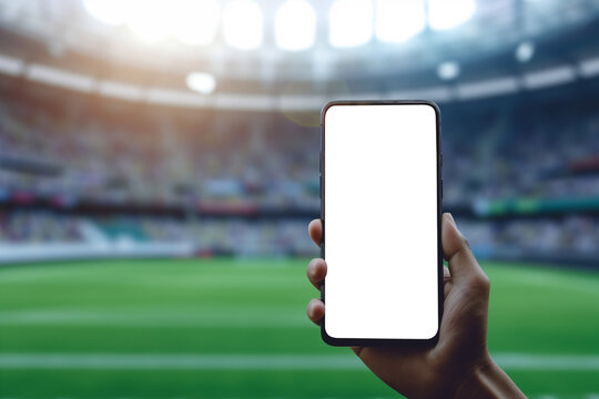 Mans hand holding a smartphone against soccer or football stadium background