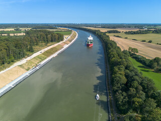 Aerial drone image of the Kiel canal, nord ostsee kanal, in Germany. Blue sky and green bank of the...