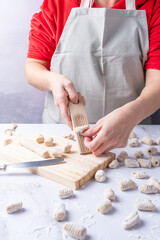 Person in kitchen apron shaping potato gnocchi.