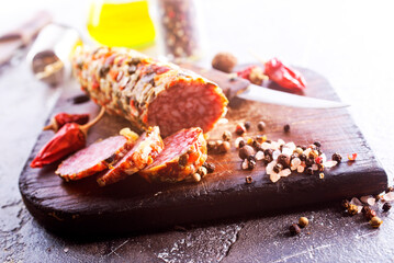 Traditional smoked salami sausage on wooden board. Slices of sausage in motion.