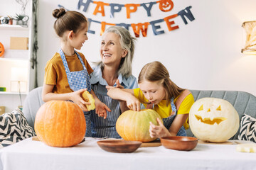 Fototapeta premium Grandmother and granddaughters carving pumpkins for halloween party, creative, hand made concept