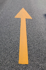 Yellow arrow pointing upwards on asphalt